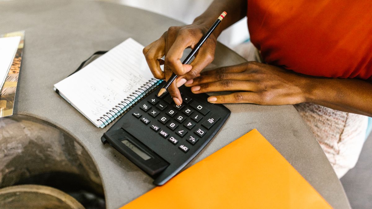 An African American woman using a calculator and notepad for budgeting