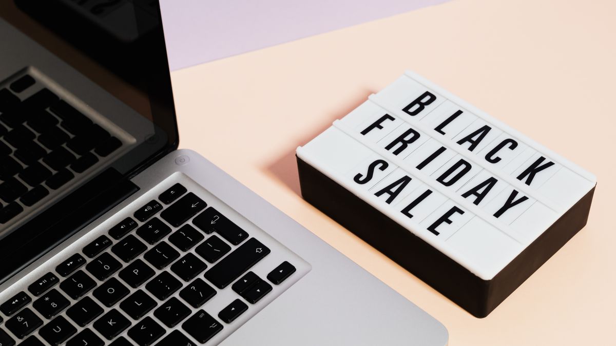 A laptop beside a lightbox sign with 'Black Friday Sale' for online shopping promotions