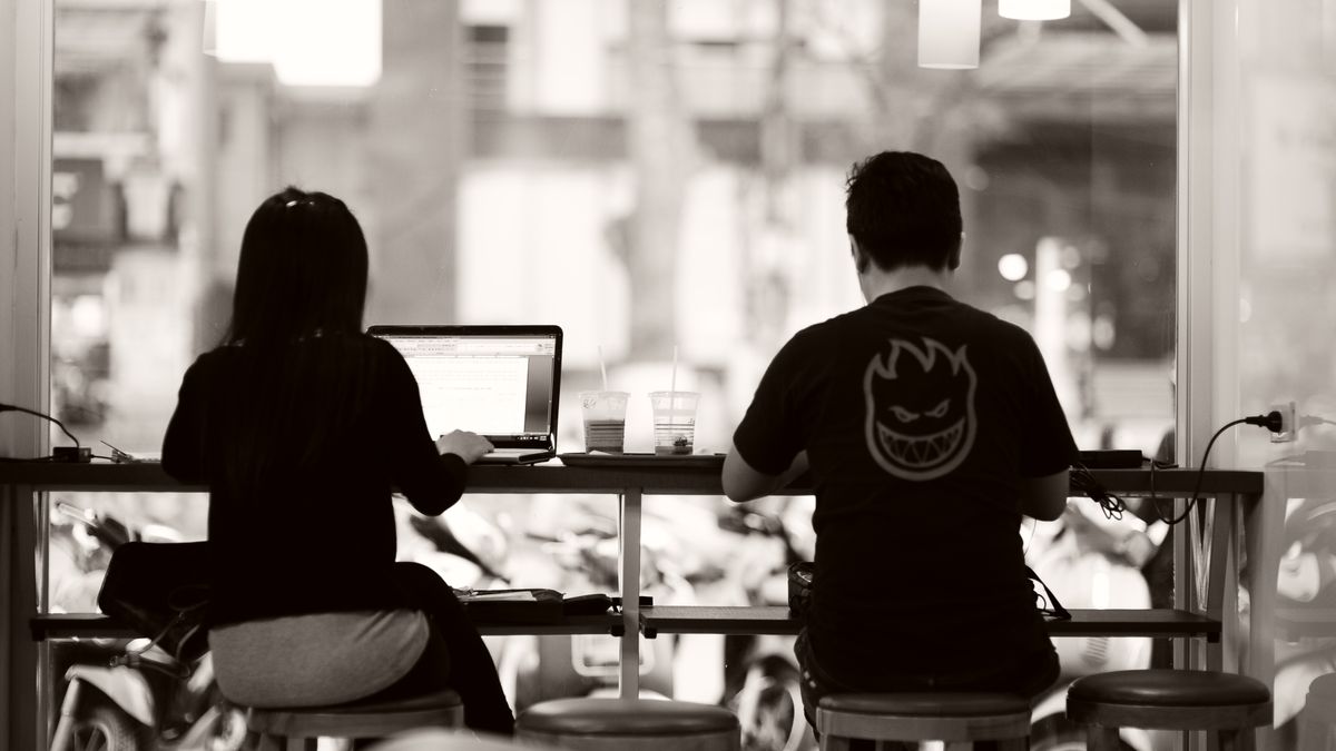 Two people working from laptops at a coffee shop, creating a modern work setting