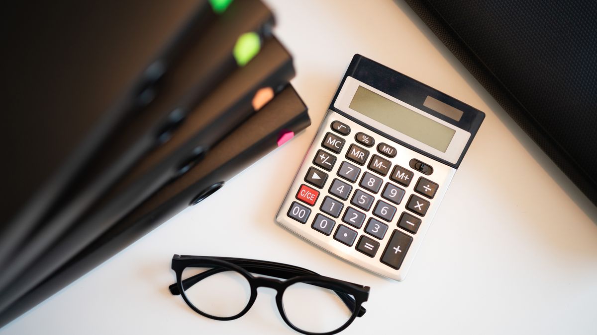 Calculator with glasses and folders on an office desk. Perfect for finance and accounting themes