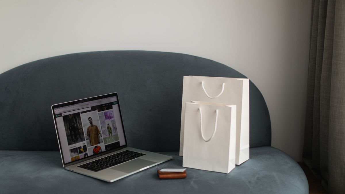 Online shopping setup with a laptop and shopping bags on a stylish couch