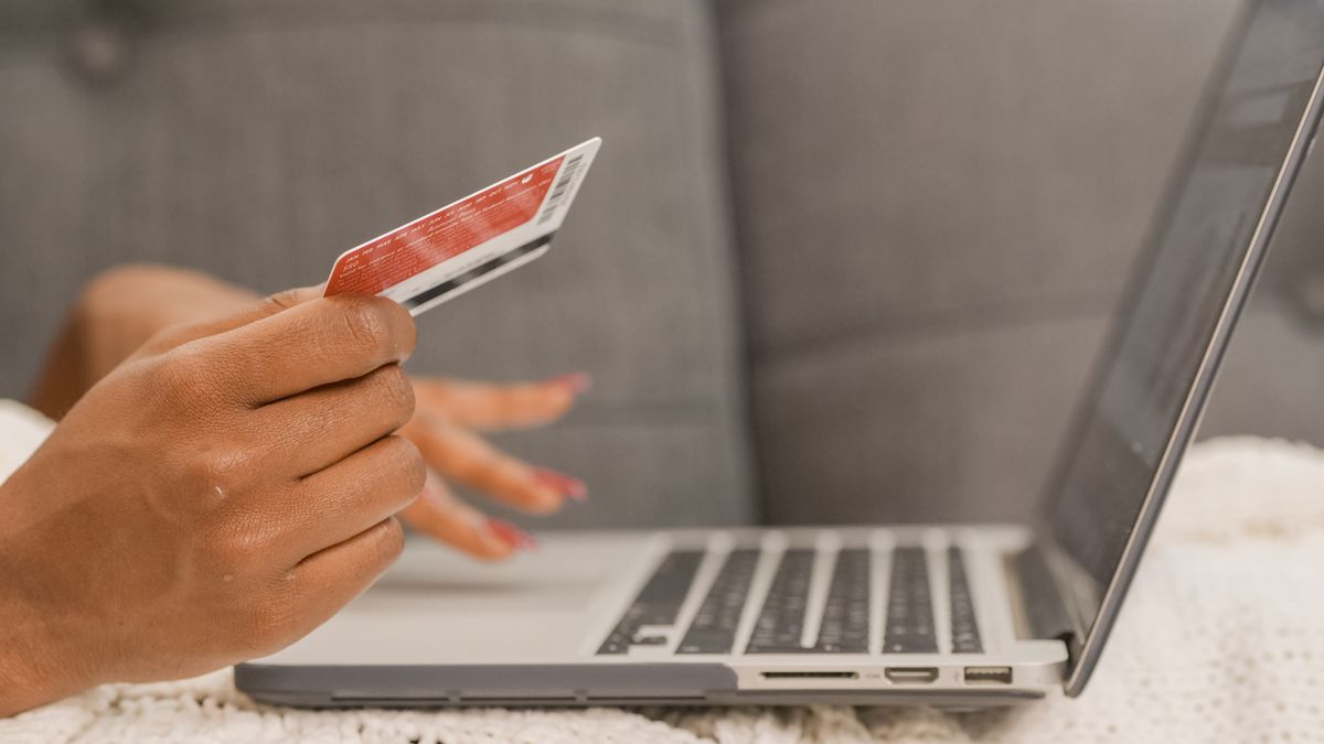 Close-up of a person using a credit card for online shopping on a laptop