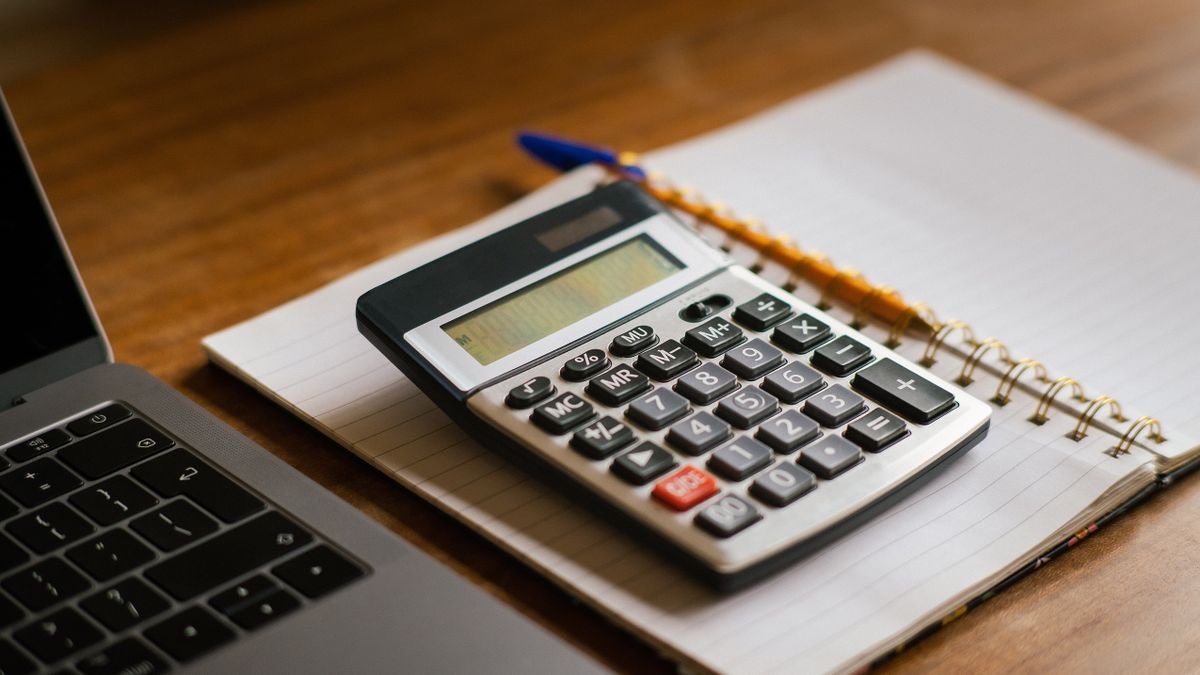 Calculator and open laptop on wooden desk, ideal for financial or accounting tasks