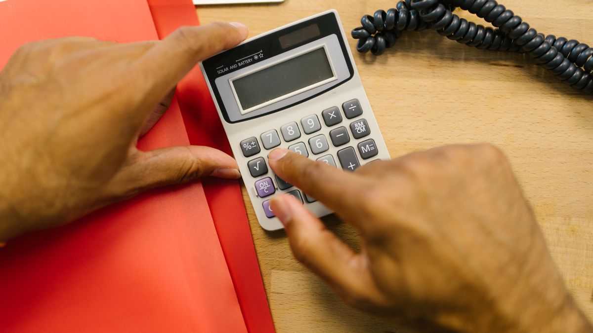 Close-up of hands using a calculator at a desk in an office setting