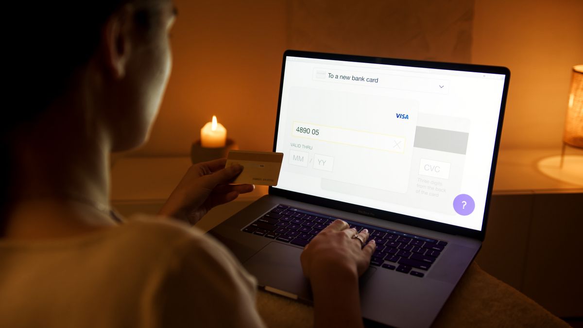 A woman makes a secure online payment using a laptop and credit card in a cozy setting