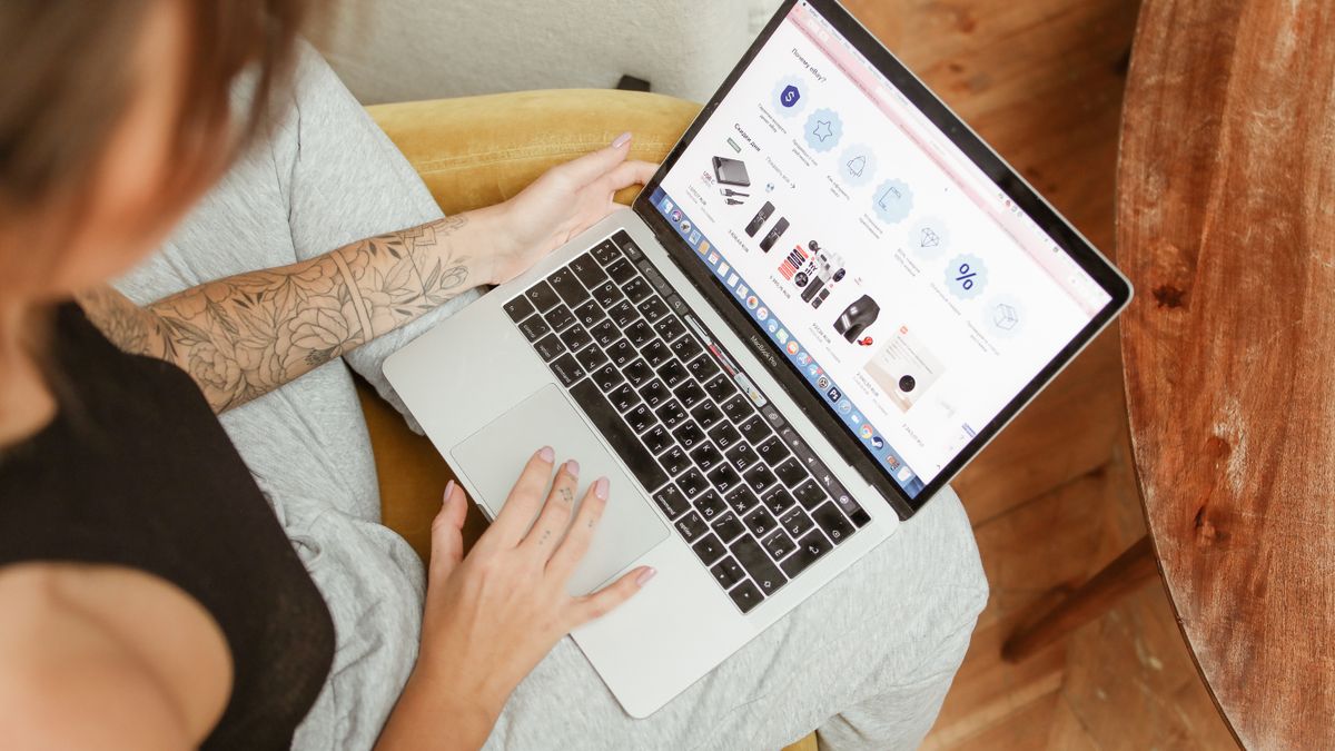 Woman with tattoos browsing online shopping site on a laptop indoors