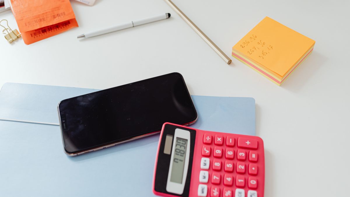 An organized office desk featuring a calculator, smartphone, and sticky notes on a white surface