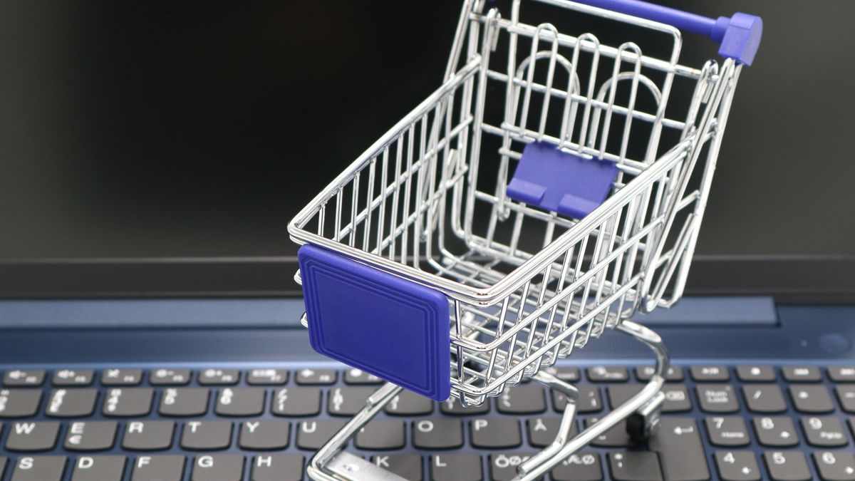 A mini shopping cart placed on a laptop keyboard, symbolizing online shopping and digital retail