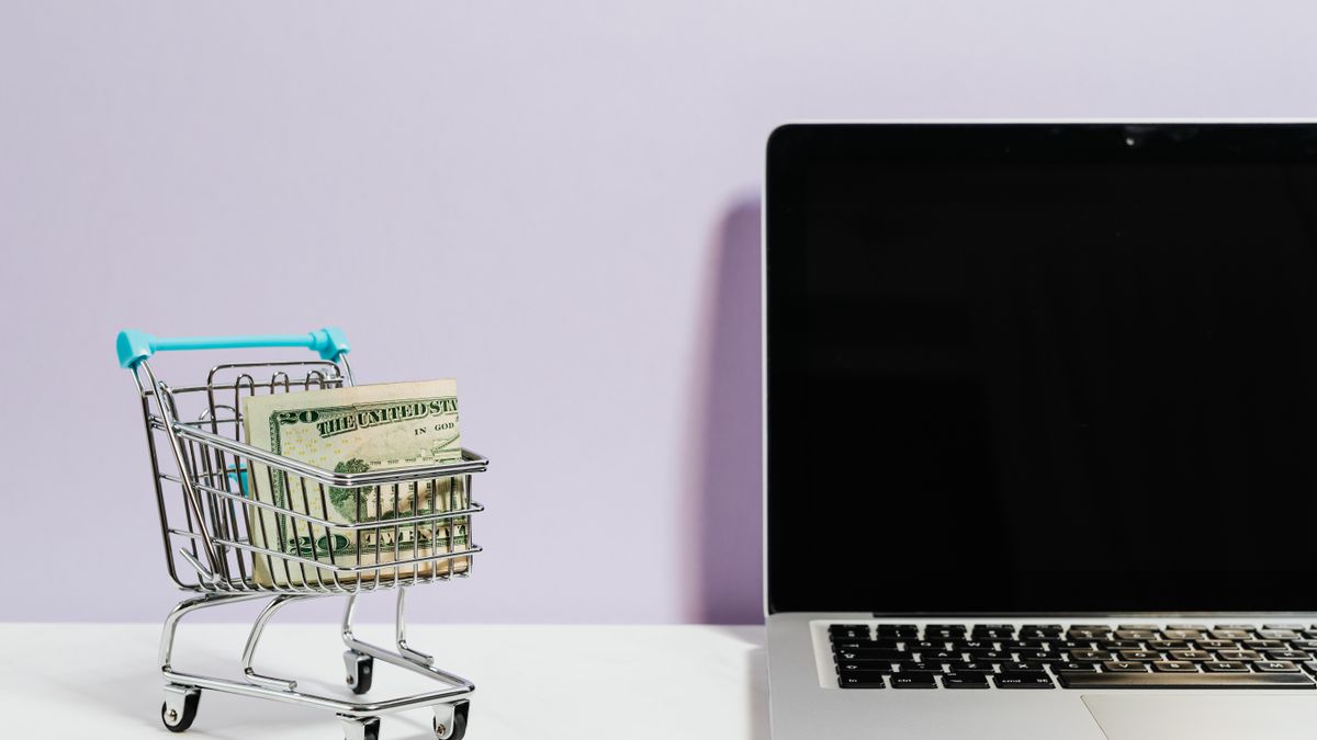 Shopping cart with money next to a laptop symbolizing online shopping and e-commerce