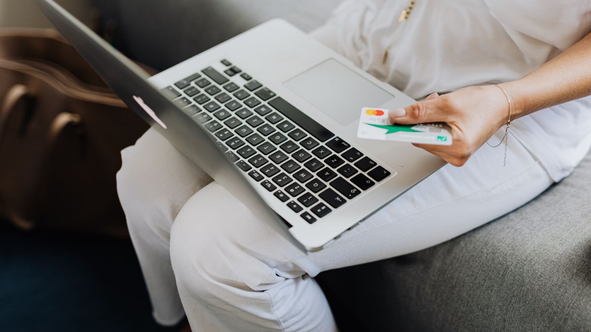 Adult using laptop and holding bank card for online shopping indoors