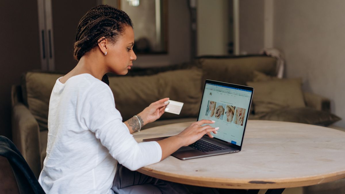 African American woman uses a credit card for an online purchase on her laptop at home