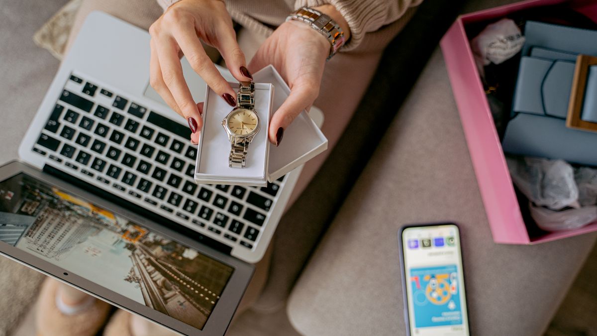 Woman unboxing a watch while online shopping using a laptop and smartphone. Perfect for lifestyle and technology themes