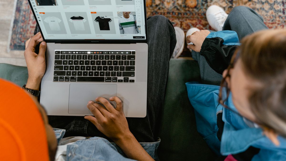 Two people browsing online clothing store on a laptop from above