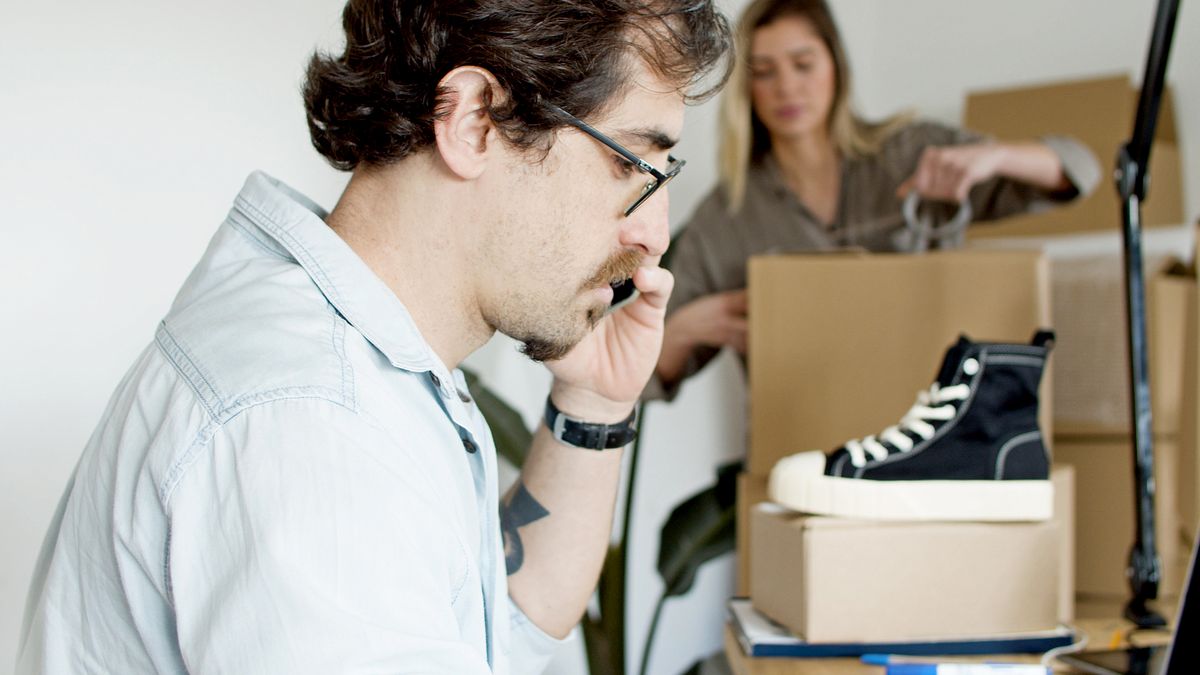 A businessman on a phone call while preparing an online order for shipping in a modern office